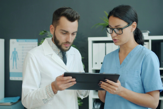 Doctor and care team member looking and working on an iPad