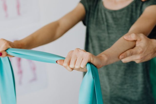 Physical therapist guiding a patient through a resistance band exercise in a clinic