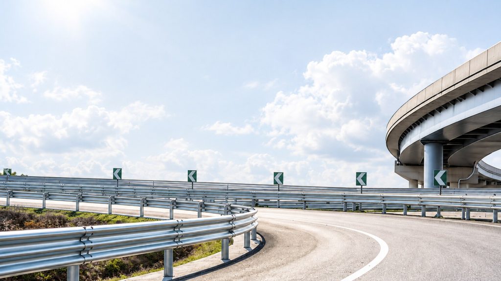 Metal guardrails curving along an empty highway under a pale hazy sky